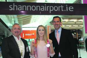 Olympic swimming qualifier Fiona Doyle from Limerick is pictured at Shannon Airport on route to Calgary in Canada where she will begin a gruelling training programme in preparation for her Olympian title bid in the 2016 Olympic Games in Rio de Janerio next August. Pictured (l-r) are Jerry O’Dea, the Mayor of Limerick Metropolitan District, Fiona Doyle with her two medals and Andrew Murphy, Chief Commercial Officer, Shannon Group plc