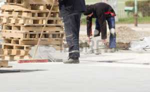 37707366-construction-worker-in-safety-clothes-cleaning-building-site-after-installing-flagstones-in-sand