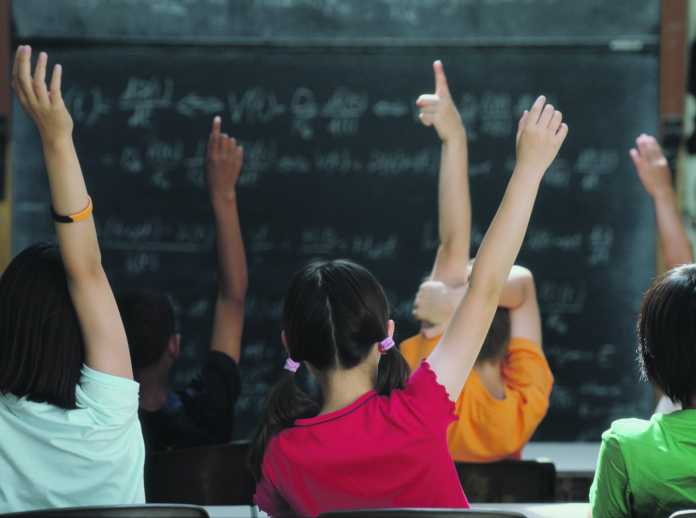 Rear view of class raising hands