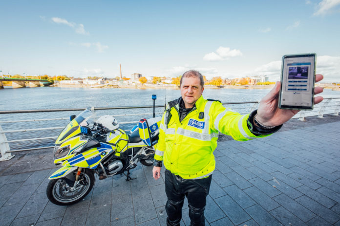 Garda Brian Duddy Limerick 16 Garda Bryan Duddy displaying the new Garda video app alongside his specially equipped BMW motorbike. Photo: Brian Arthur