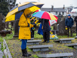 A member ofthe group holds daffodils to place on the gravesite in Mount St Lawrence Cemetery. Photo: Cian Reinhardt
