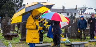 A member ofthe group holds daffodils to place on the gravesite in Mount St Lawrence Cemetery. Photo: Cian Reinhardt