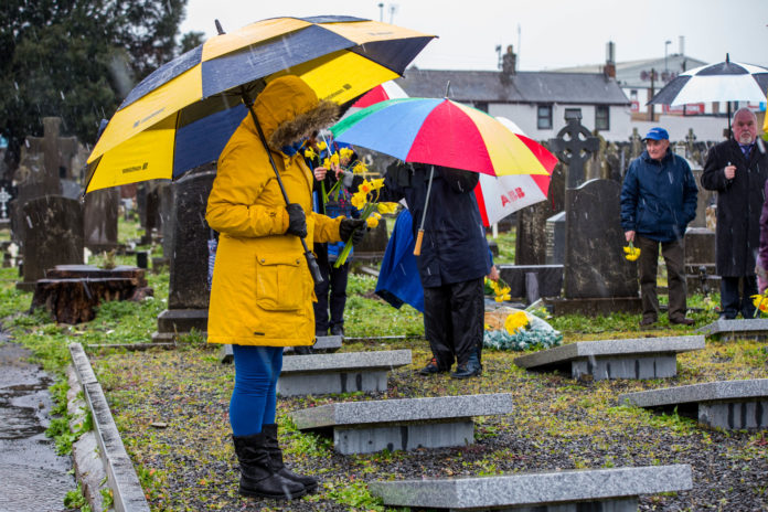 A member ofthe group holds daffodils to place on the gravesite in Mount St Lawrence Cemetery. Photo: Cian Reinhardt