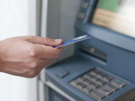Hand inserting ATM card into bank machine to withdraw money. businessman men hand puts credit card into ATM