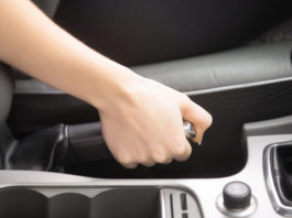 Close up of female hands holding a handbrake lever to keep the vehicle stationary