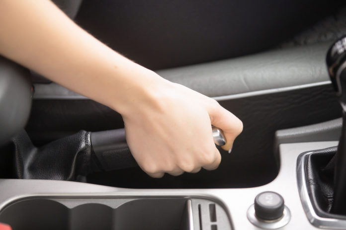 Close up of female hands holding a handbrake lever to keep the vehicle stationary