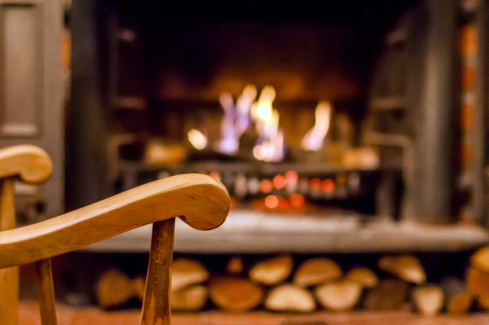 Home comfort. Rocking chair near the fireplace. Photo of interior of room. Rocking chair in the living room with decorated modern fireplace