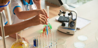 Close-up image of children filling test-tubes with different reagents