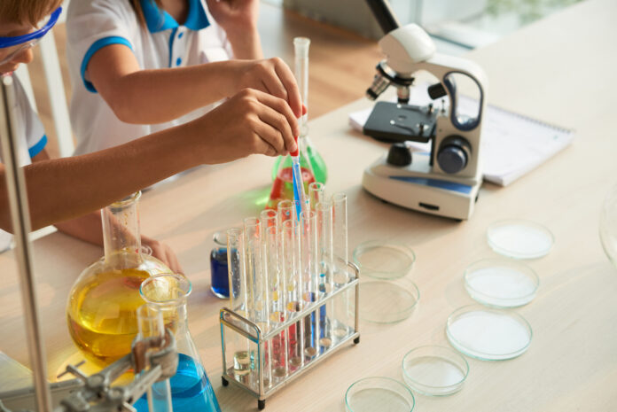 Close-up image of children filling test-tubes with different reagents