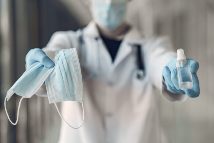 Doctor hold the antiseptic and masks in his hand Doctor hold the antiseptic and masks in his hand