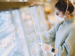 Woman in a supermarket. Lady in a respirator. Girl makes parchases.