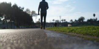 person in black jacket and pants walking on gray concrete road during daytime