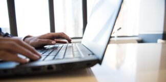 person using black laptop on brown table