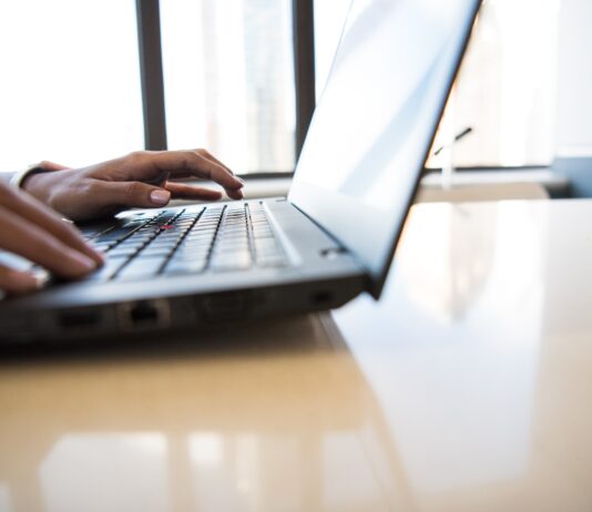 person using black laptop on brown table