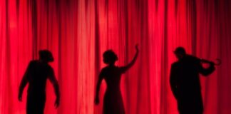 silhouette of three performers on stage