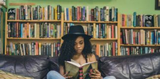 woman reading a book while sitting on black leather 3-seat couch