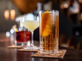 clear drinking glass with orange liquid on brown wooden table