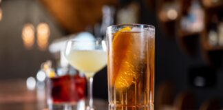 clear drinking glass with orange liquid on brown wooden table