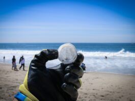 person holding round white ball near body of water during daytime