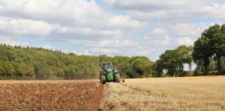 green tractor farming in field