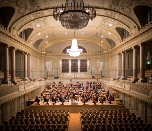 music group performing on stage with empty audience seats