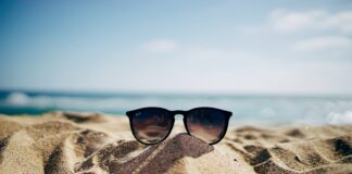 black Ray-Ban Wayfarer sunglasses on beach sand