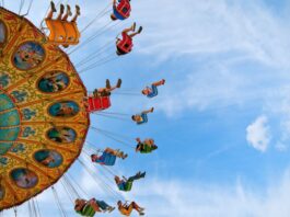 people riding carnival ride under blue skies