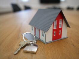 white and red wooden house miniature on brown table