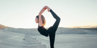 shallow focus photo of woman in black sleeveless shirt doing yoga