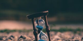 selective focus photo of brown and blue hourglass on stones