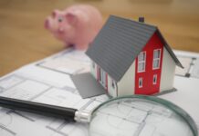 white and red wooden house beside grey framed magnifying glass