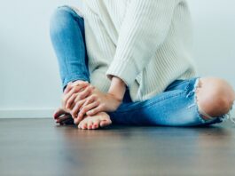 person wearing distressed blue denim jeans inside room