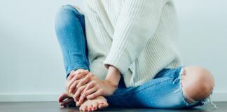 person wearing distressed blue denim jeans inside room