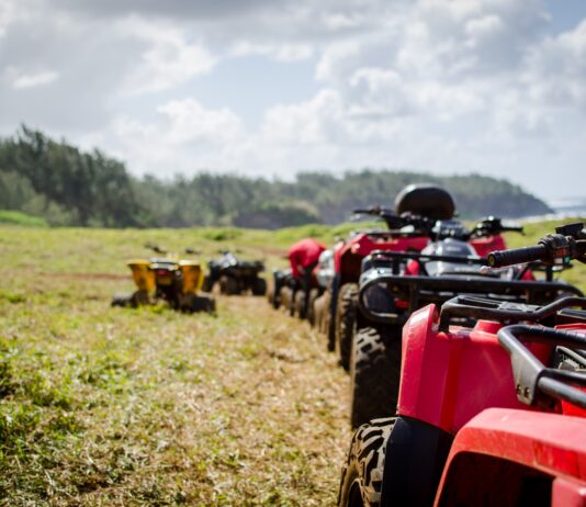 focus photography of ATV's falling in line on grass field