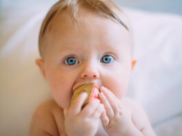 selective focus photography of baby holding wooden cube