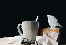 white ceramic mug on white table beside black eyeglasses