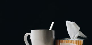 white ceramic mug on white table beside black eyeglasses