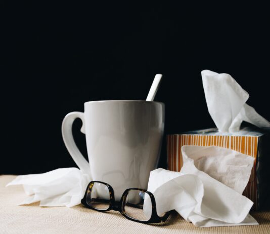 white ceramic mug on white table beside black eyeglasses